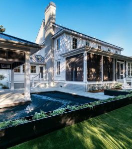 Backyard of two story home featuring pool, grass and potted plants