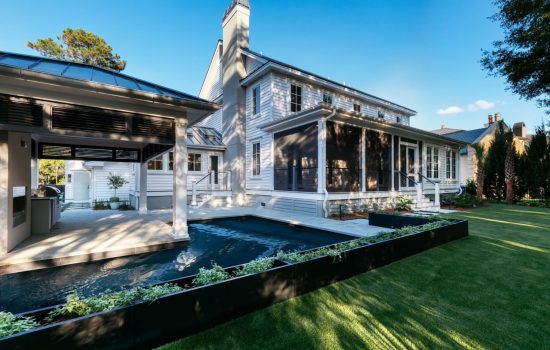 Backyard of two story home featuring pool, grass and potted plants