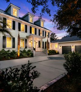 Two Story home with white siding, featuring lit windows and landscape lighting